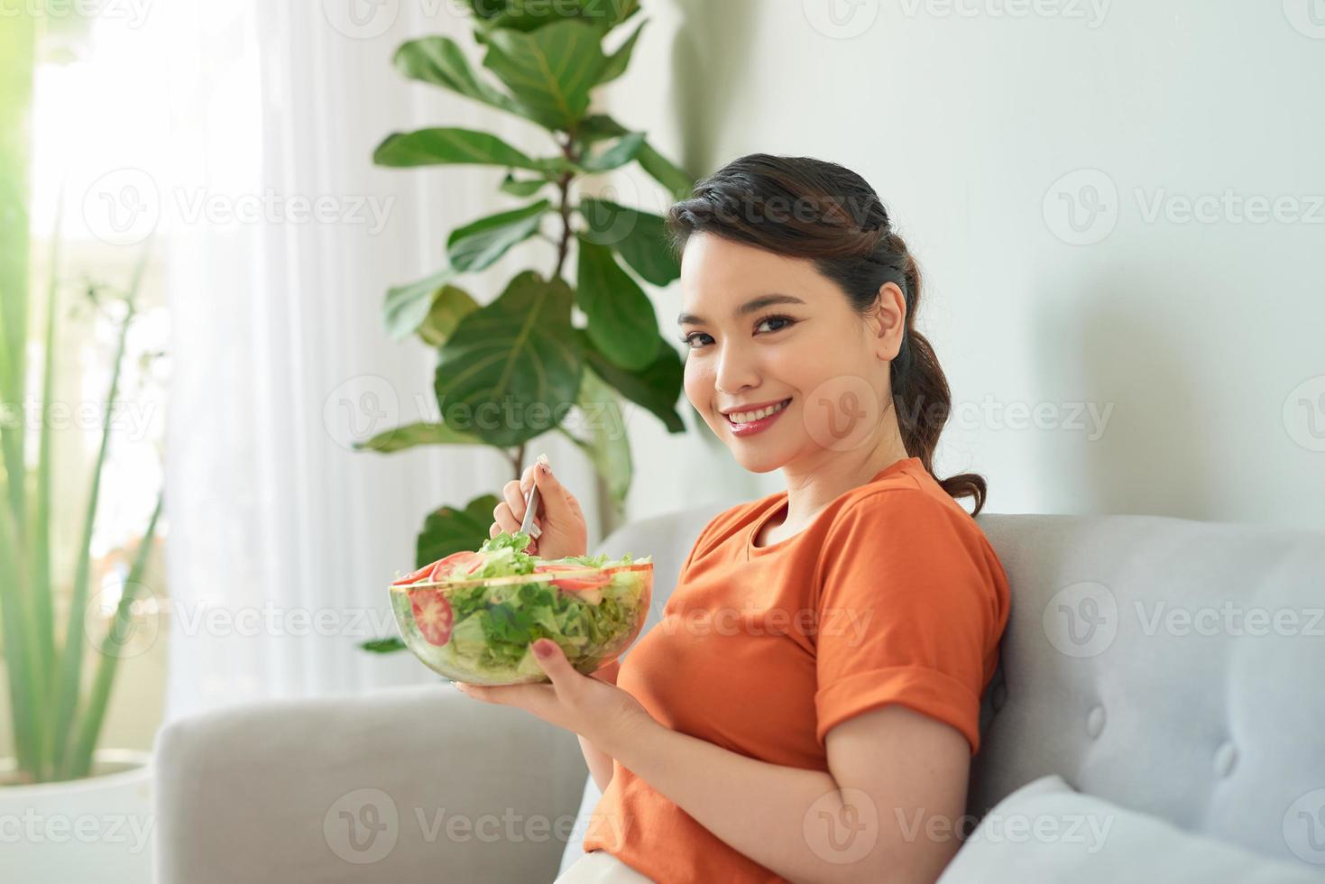 primer plano de una hermosa mujer asiática comiendo ensalada en casa. foto