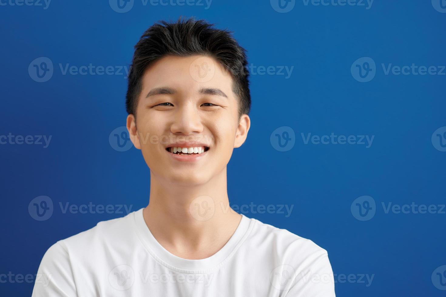 joven cara brazos cruzados con cara sonriente. hombre asiático de pie al aire libre. retrato gente de asia con camiseta blanca. foto