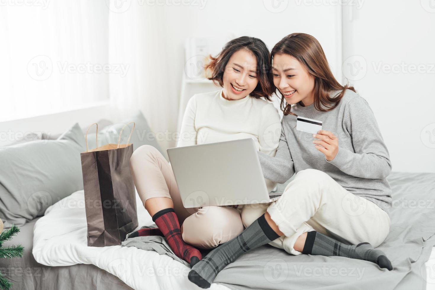 dos mujeres jóvenes y mejores amigas haciendo compras en línea en casa con una computadora portátil y una tarjeta de crédito foto