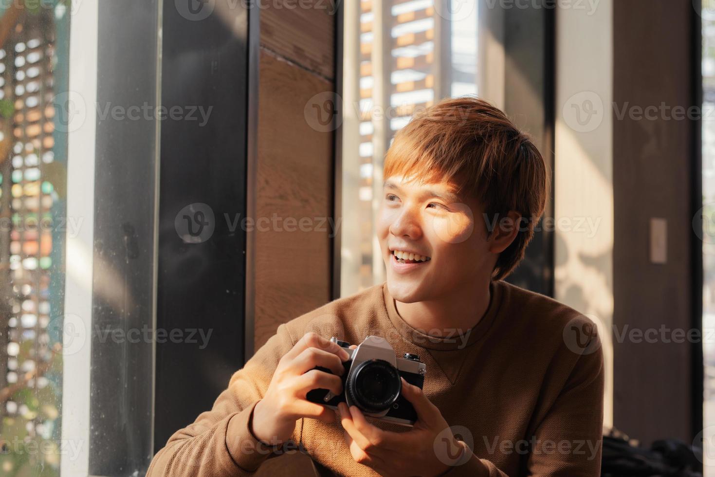 Asian man using camera sitting in a cafe. photo