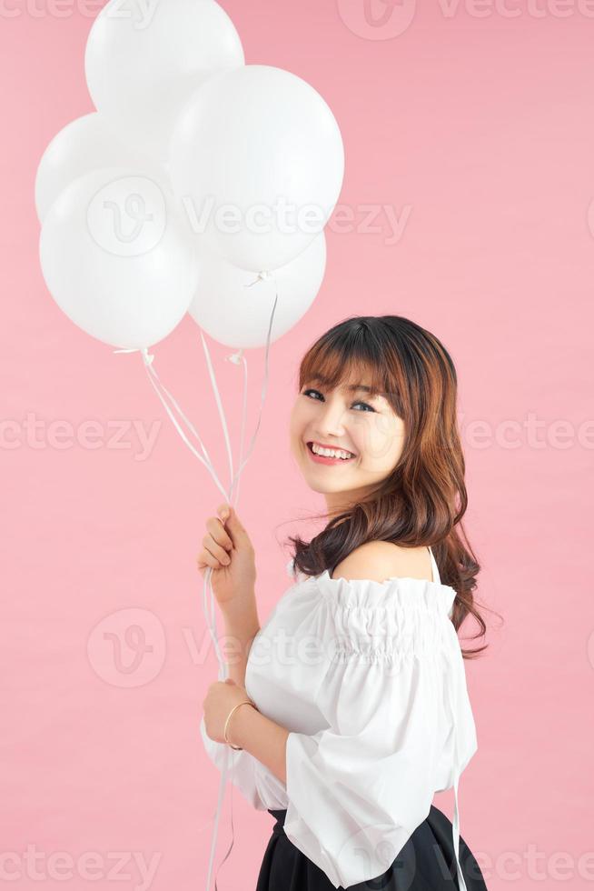 Portrait of asian appearance stand with pink air balloons, raised hands up. Happy photo