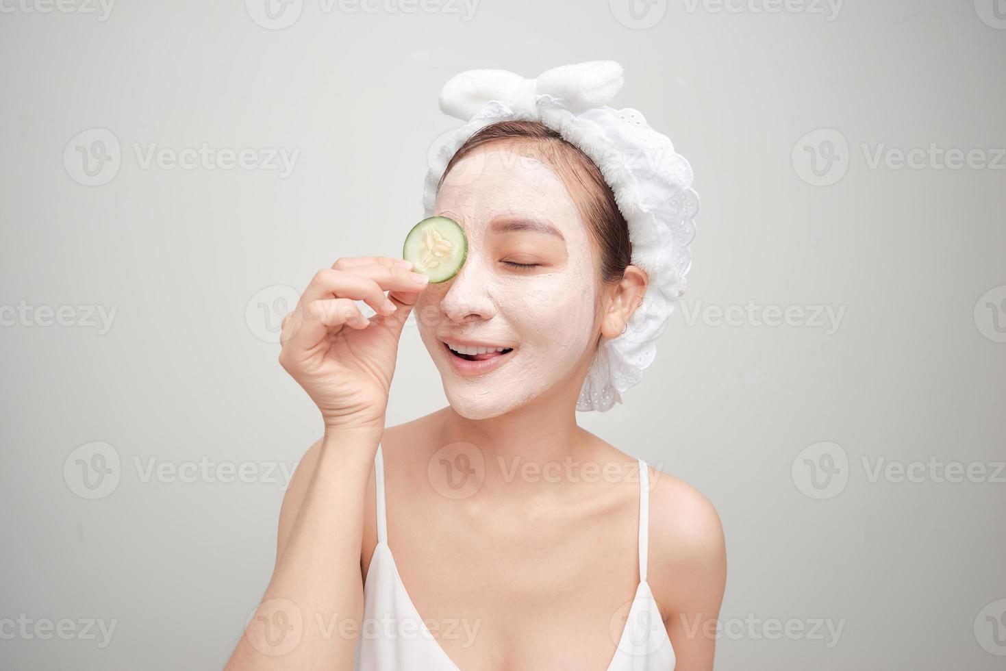 Attractive young woman covering her eyes with cucumbers on a blue background. Clay mask. photo