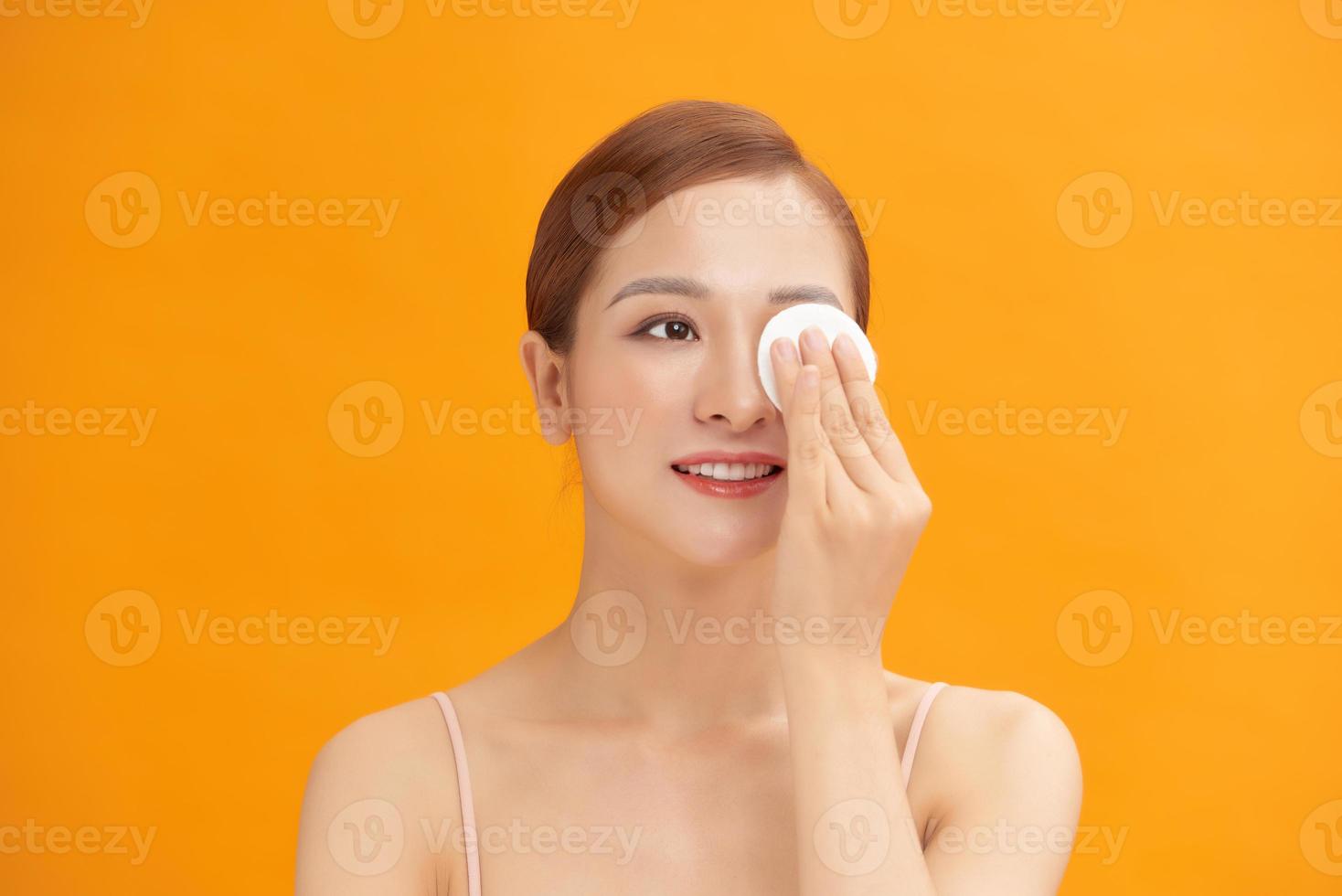 Happy smiling beautiful asian woman using cotton pad cleaning skin photo