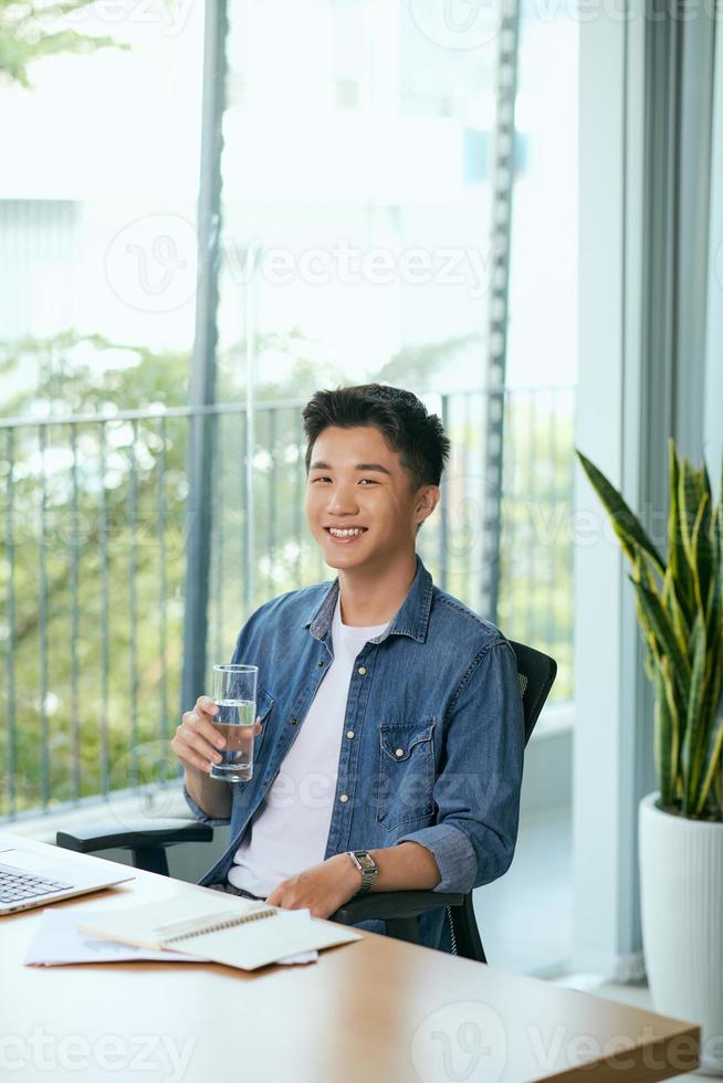 Portrait of a young business man using laptop computer while and smartphone working. photo