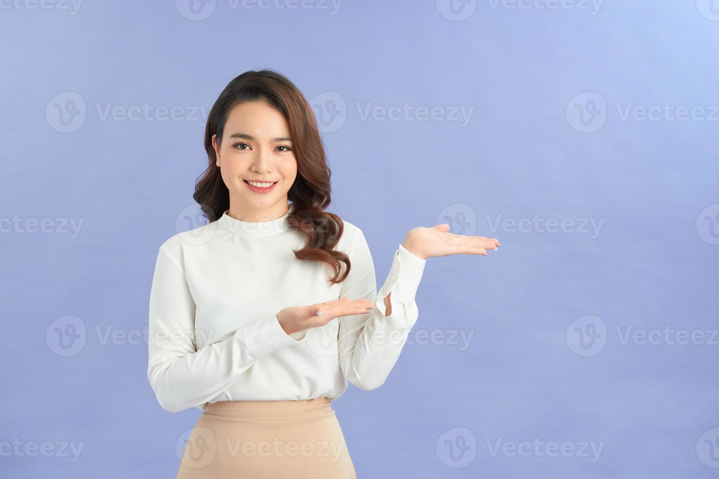 Full length portrait of a happy thoughtful woman holding copyspace on the palm isolated on a purple background photo