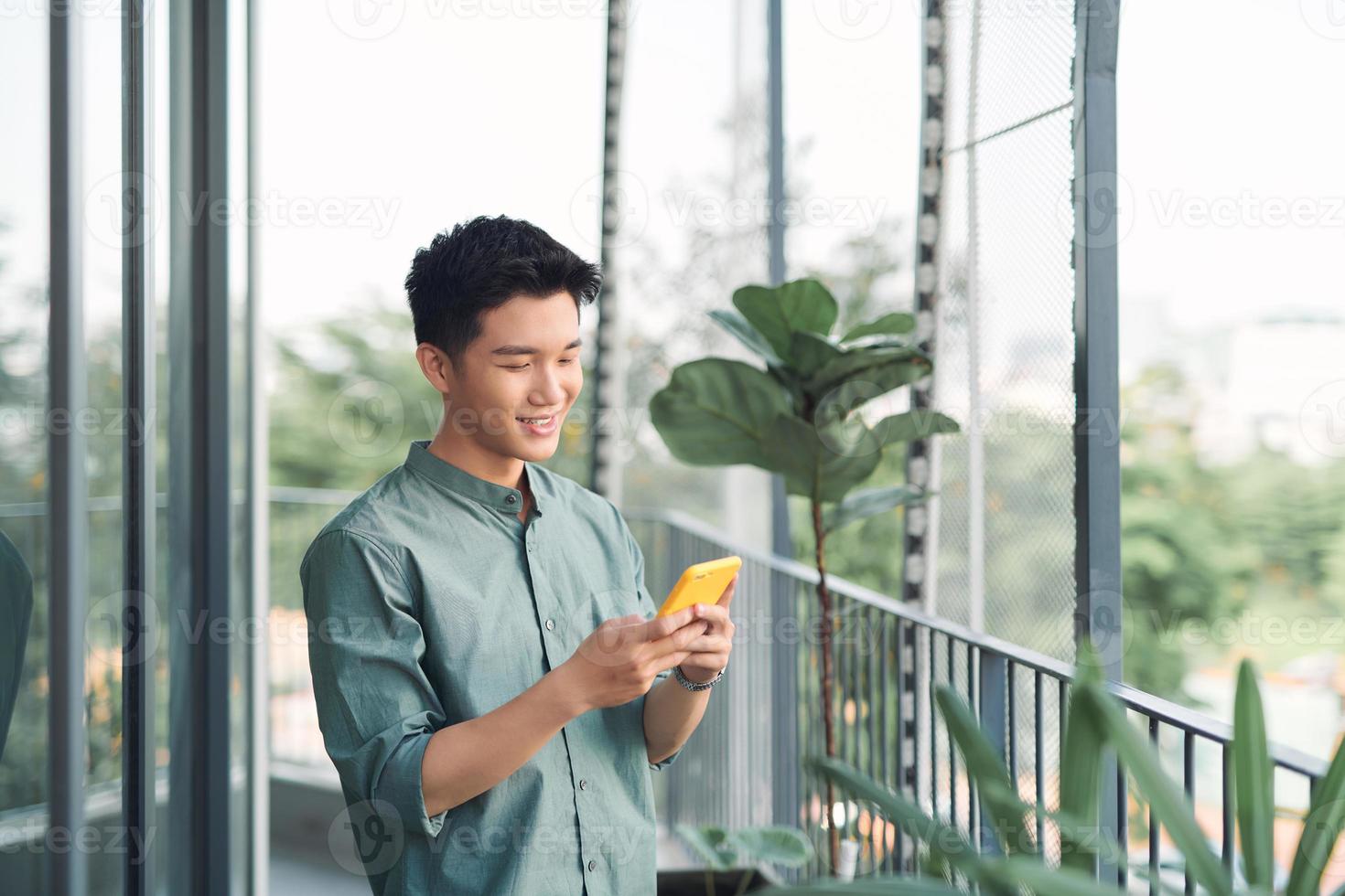 Asian young man using smartphone on balcony photo