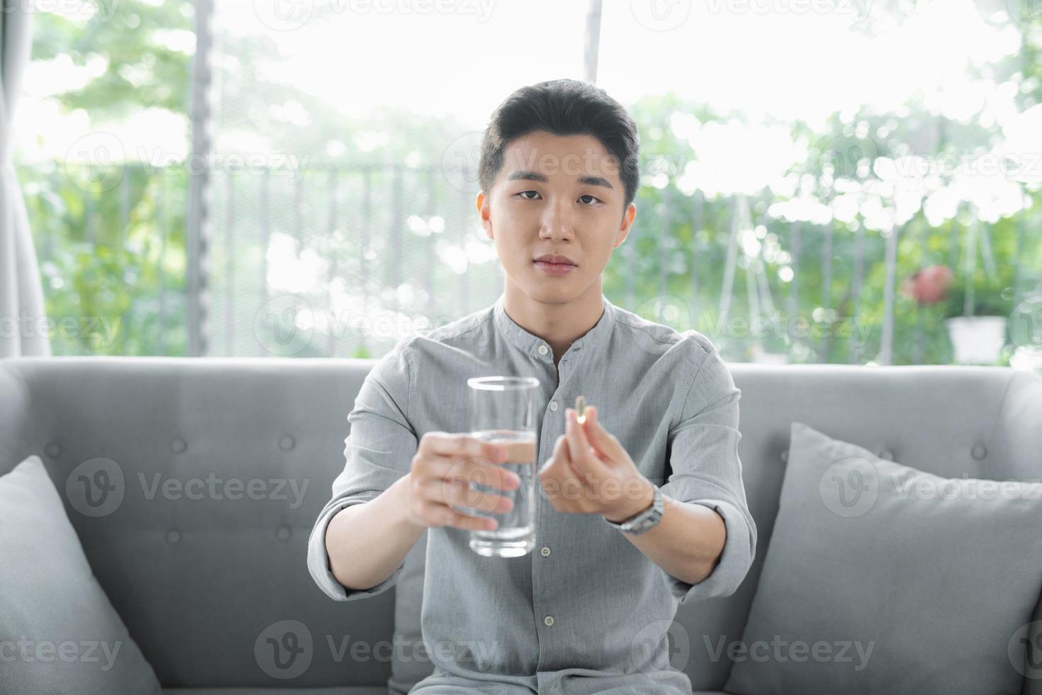 Smiling handsome man holding omega 3 soft gel pill in his fingers. photo