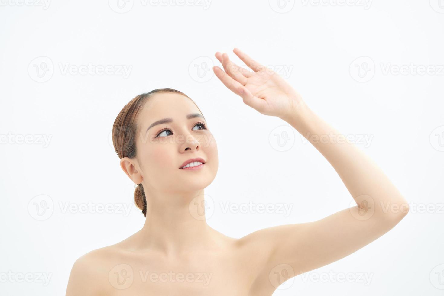 Close up of young naked Asian woman looking up and showing hand. Isolated on white background. photo