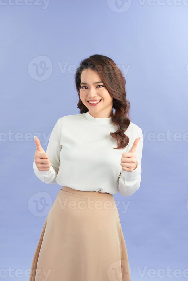 Image of cheerful young lady standing isolated over purple background. Looking camera showing thumbs up. photo