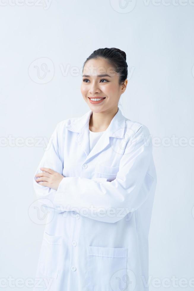 Portrait of glad smiling doctor in white uniform standing with crossed hands on white background photo