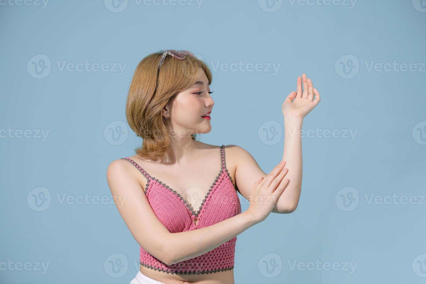 Portrait of beauty smiling asian woman applying a lotion to her arm skin during her dressing up. photo