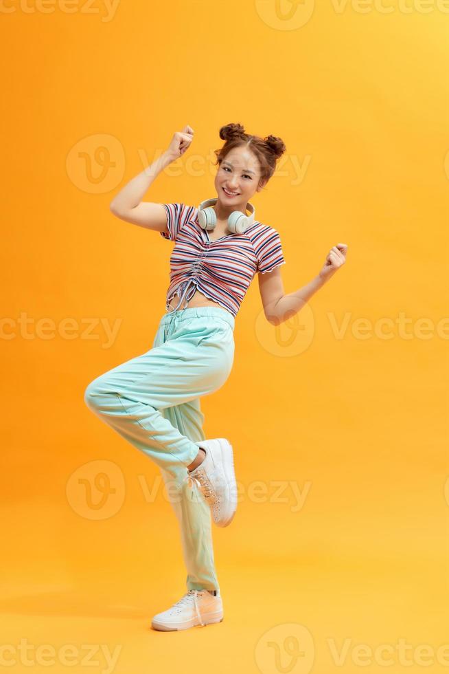 Lady in great mood jumping with raised hands on yellow background. photo