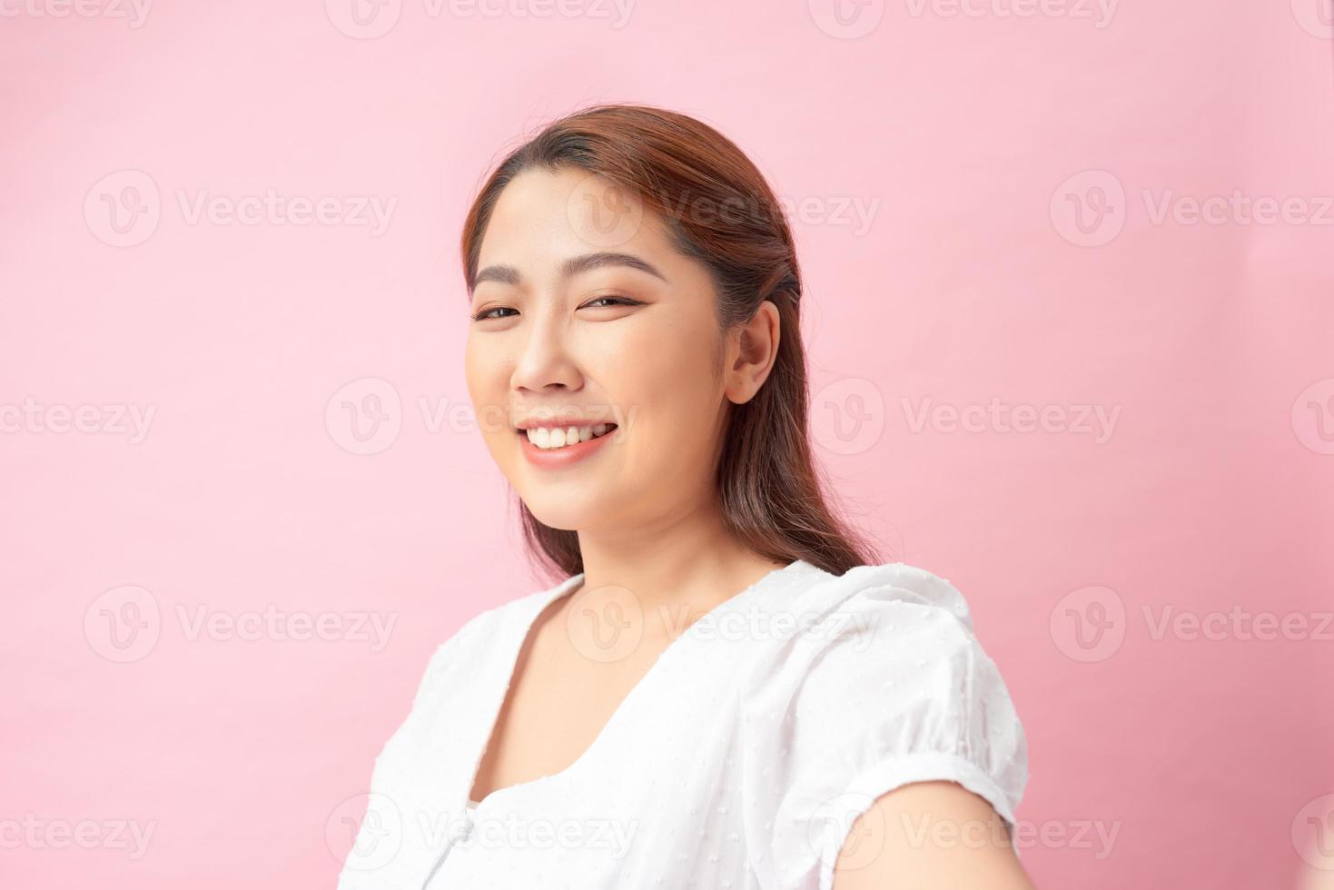 Close-up of young beautiful woman taking selfie. Isolated pink background photo