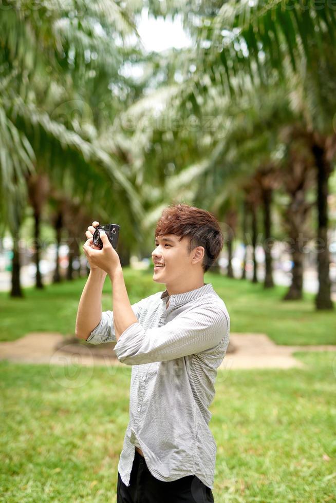 Young asian tourist man smiling happy using vintage camera at the city. photo