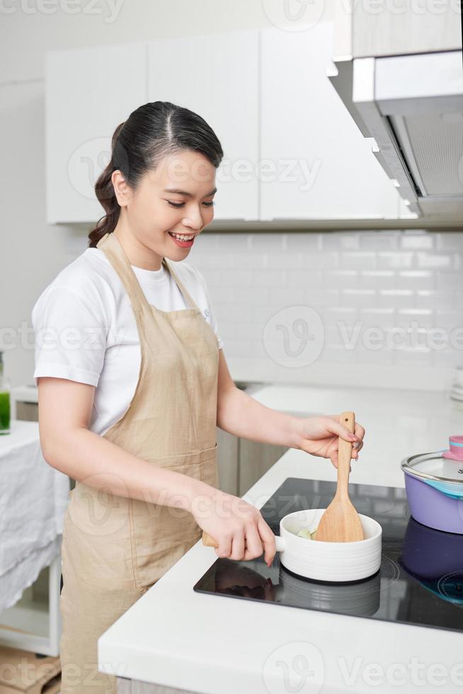 Cooking woman in kitchen with wooden spoon photo