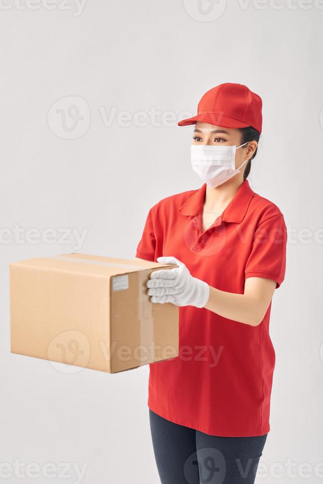 repartidora sosteniendo cajas de cartón con guantes médicos de goma y máscara sobre fondo blanco. foto