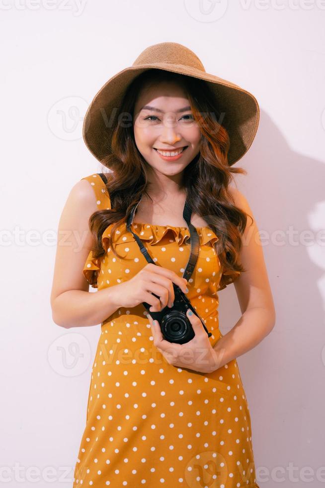 mujer joven feliz sosteniendo una cámara de fotos retro, aislada en un fondo pastel