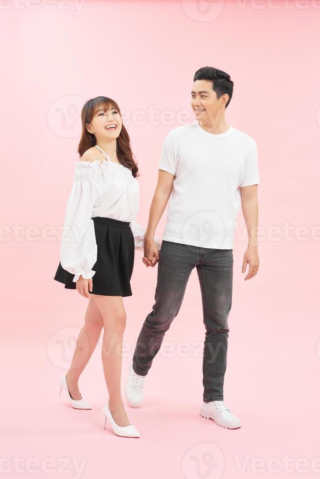 Studio shot of beautiful young couple walking together and holding hands photo