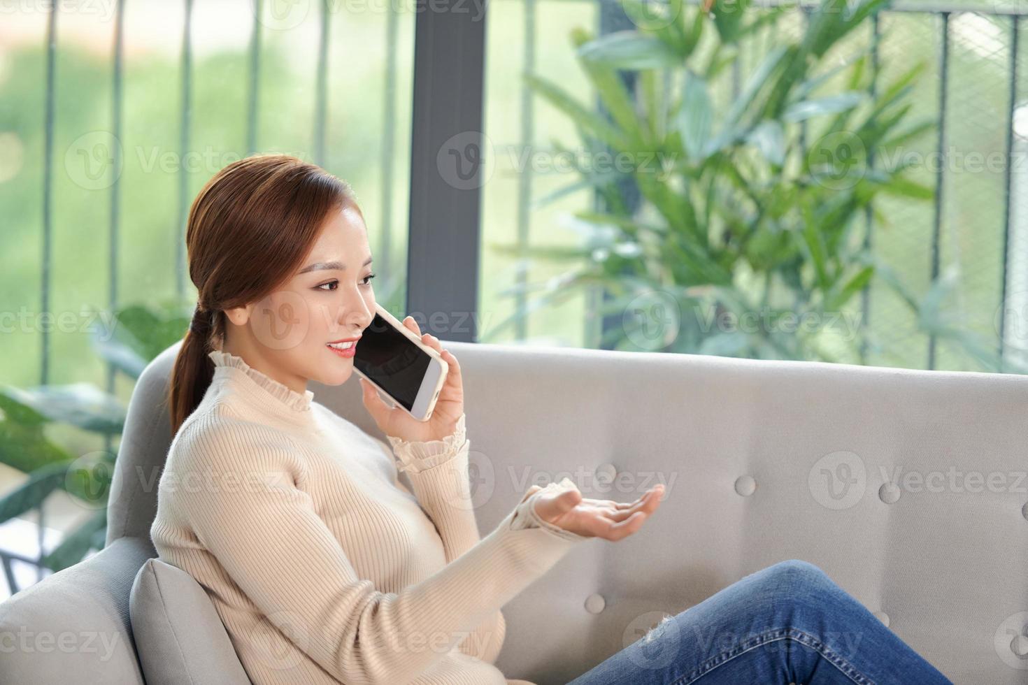 Picture of happy adult woman using phone at home in the living room photo
