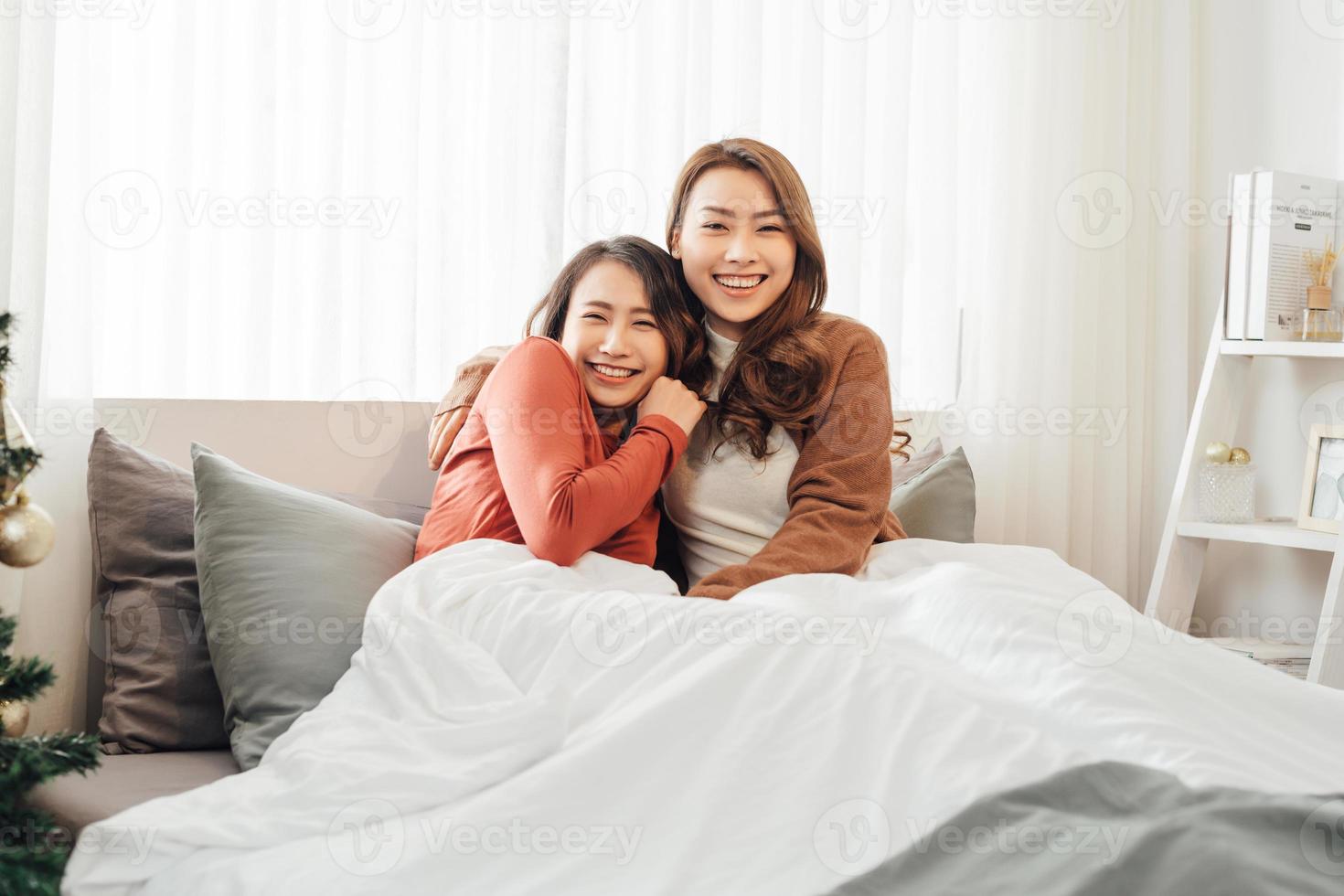 Two asian beautiful women or lesbian laying down and playing together on cozy bed. photo