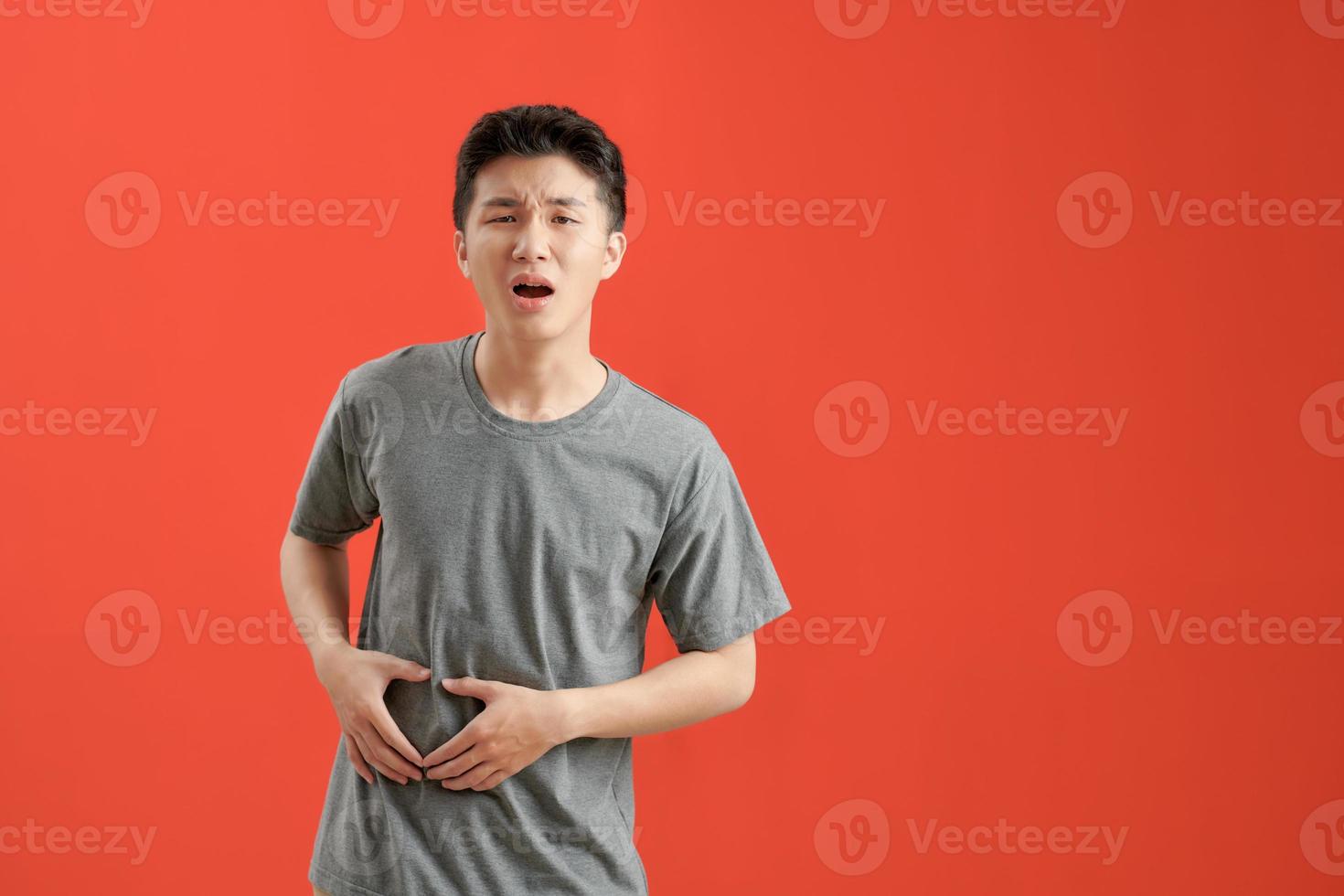 Young asian man wearing a white tshirt sick, suffering from stomachache, painful disease concept. photo