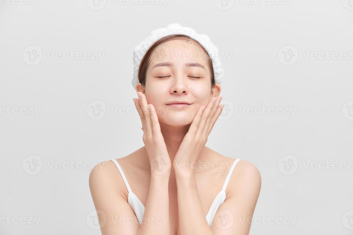 Happy young girl with clean skin and with a white towel on her head washes face photo