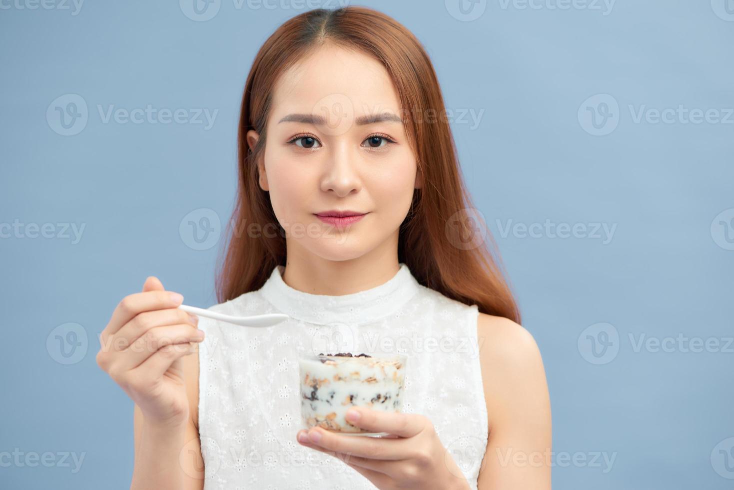 hermosa joven comiendo yogur fresco, pasas y avena para el desayuno. foto