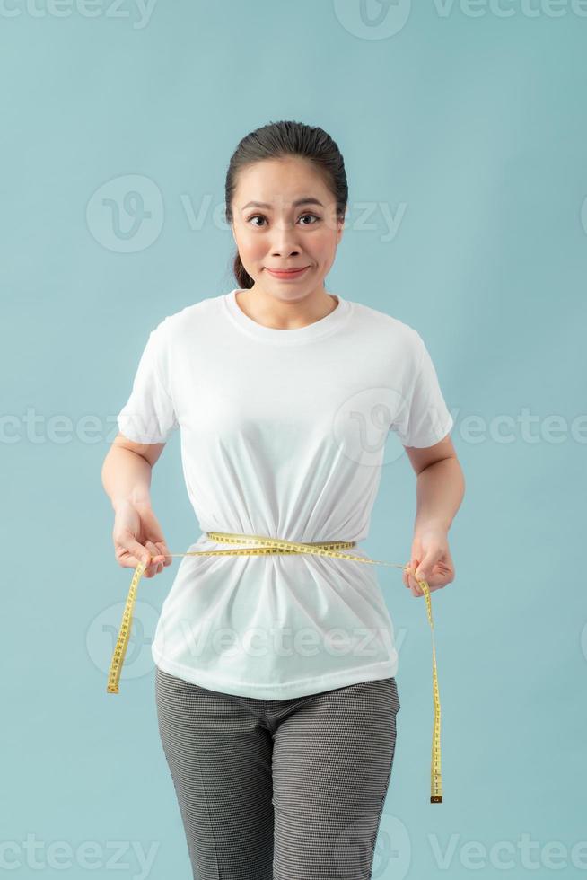 control de peso del cuidado del cuerpo saludable de las mujeres que mide la grasa de la cintura usando cinta métrica o cinta métrica. foto