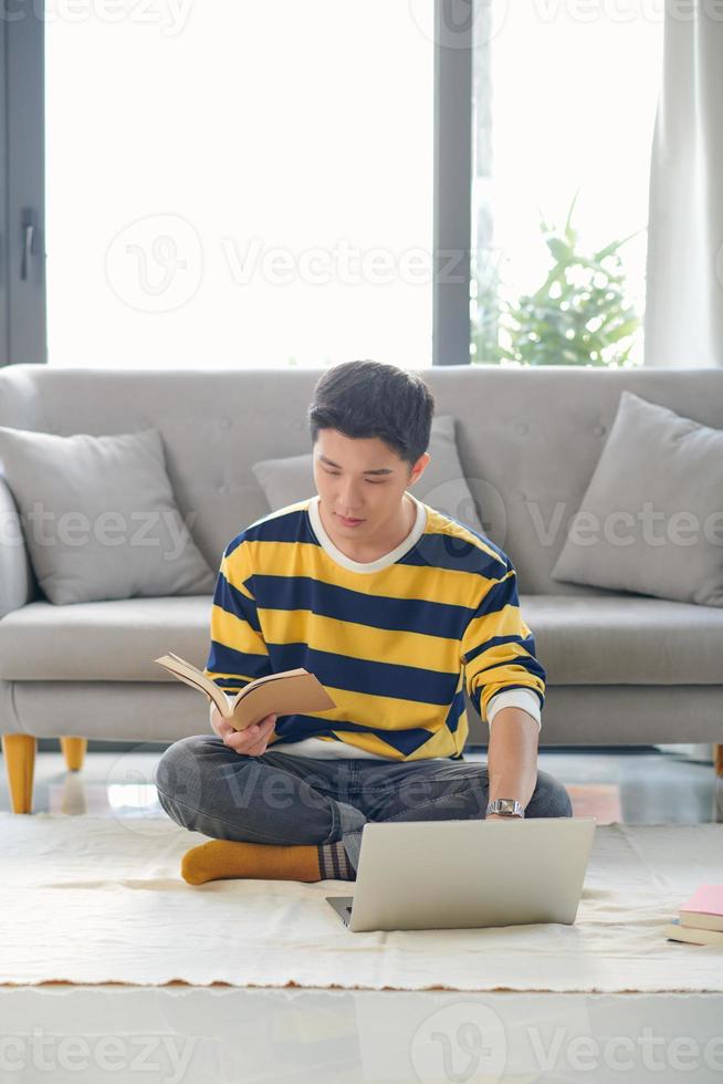 Asian man sitting on the floor and making making financial calculations online business in new apartment photo