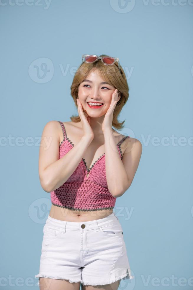 Sexy carefree woman posing near blue wall in studio. photo