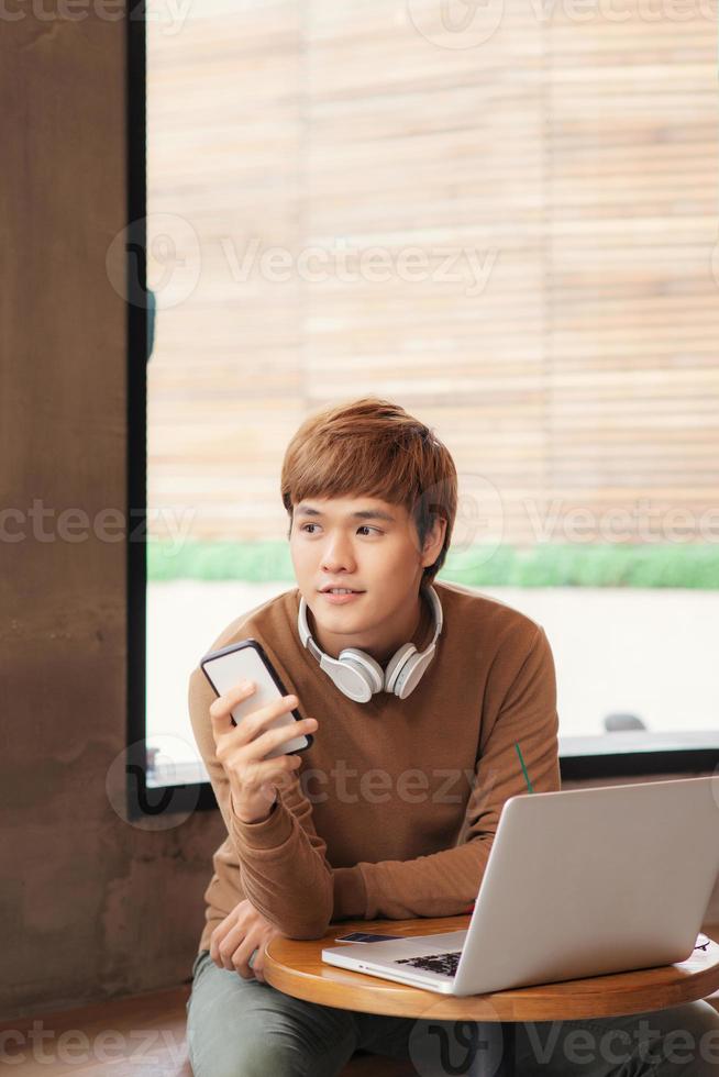 Smiling young man using gadgets at coffee shop photo