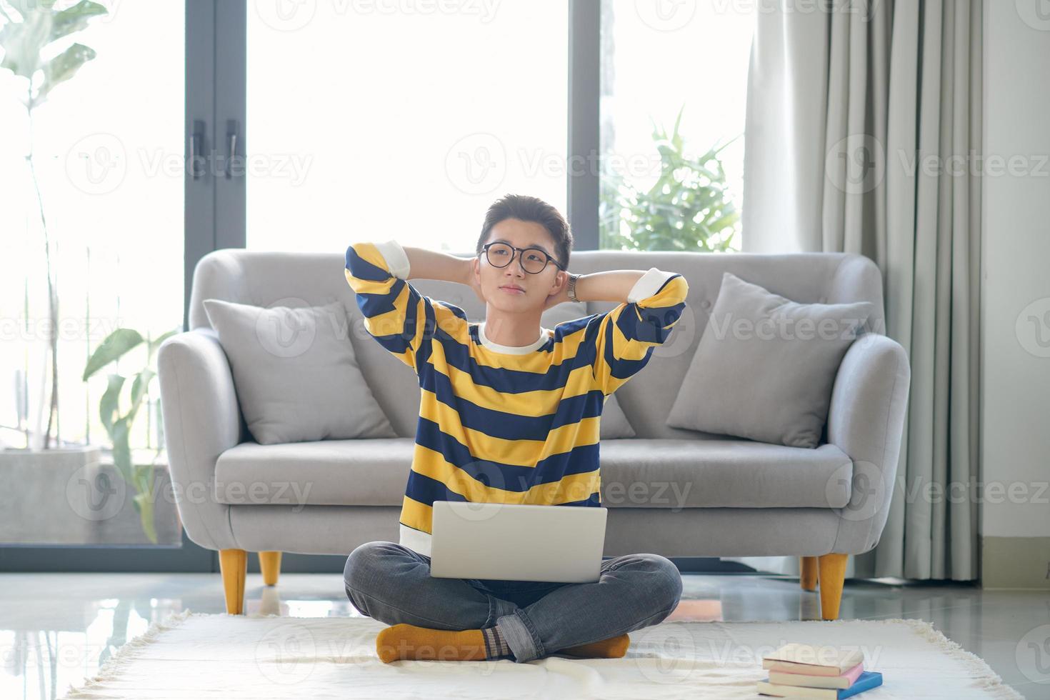 Asian student with a lot of books and laptop preparing for exam at home photo