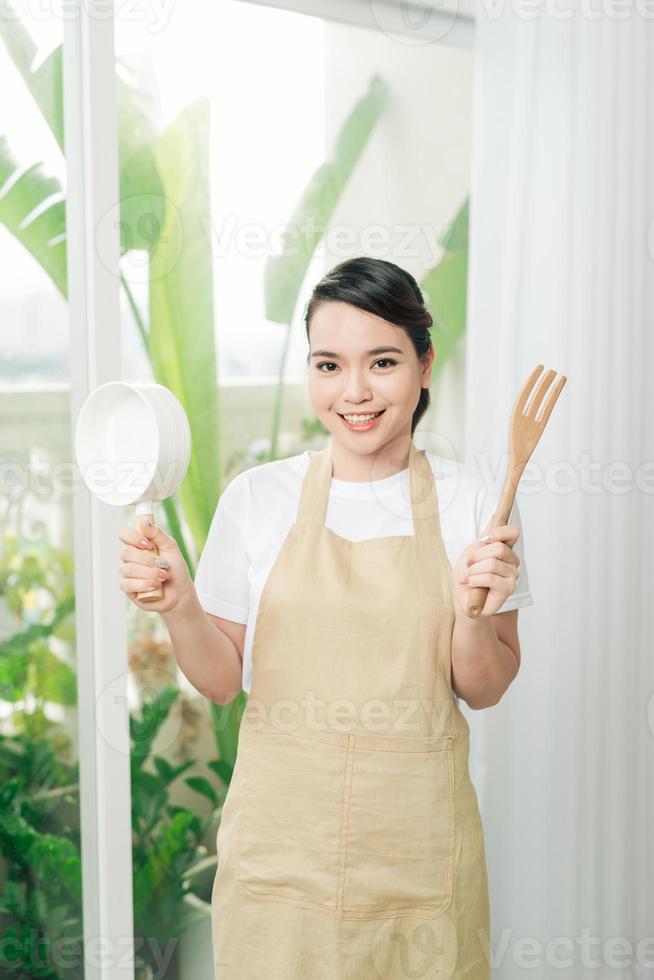 Young woman wearing kitchen apron with pan photo
