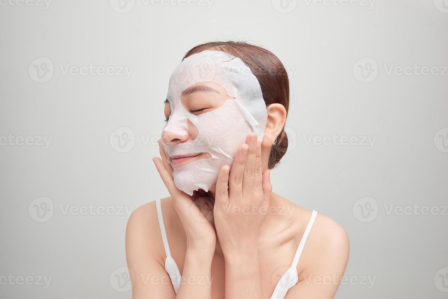 Young girl with facial mask looking at camera over white background. Cosmetic procedure. Beauty spa and cosmetology. photo