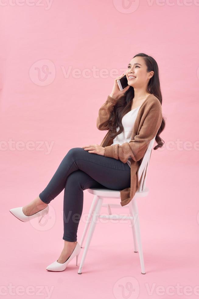 Young woman talking by mobile phone on color background photo