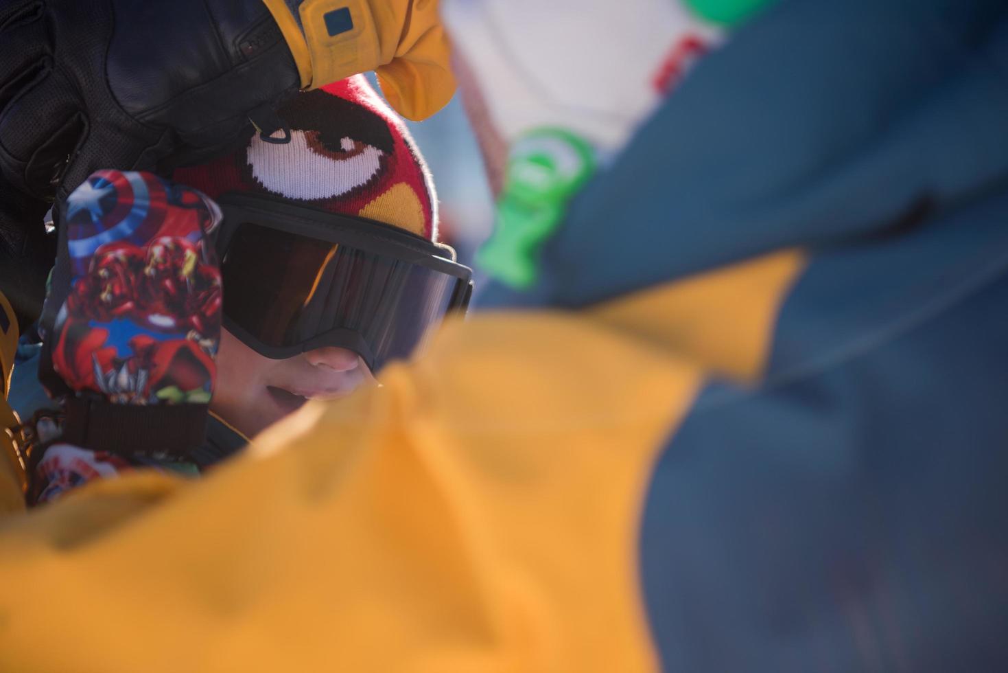 father preparing his little son for the first time on a snowboard photo