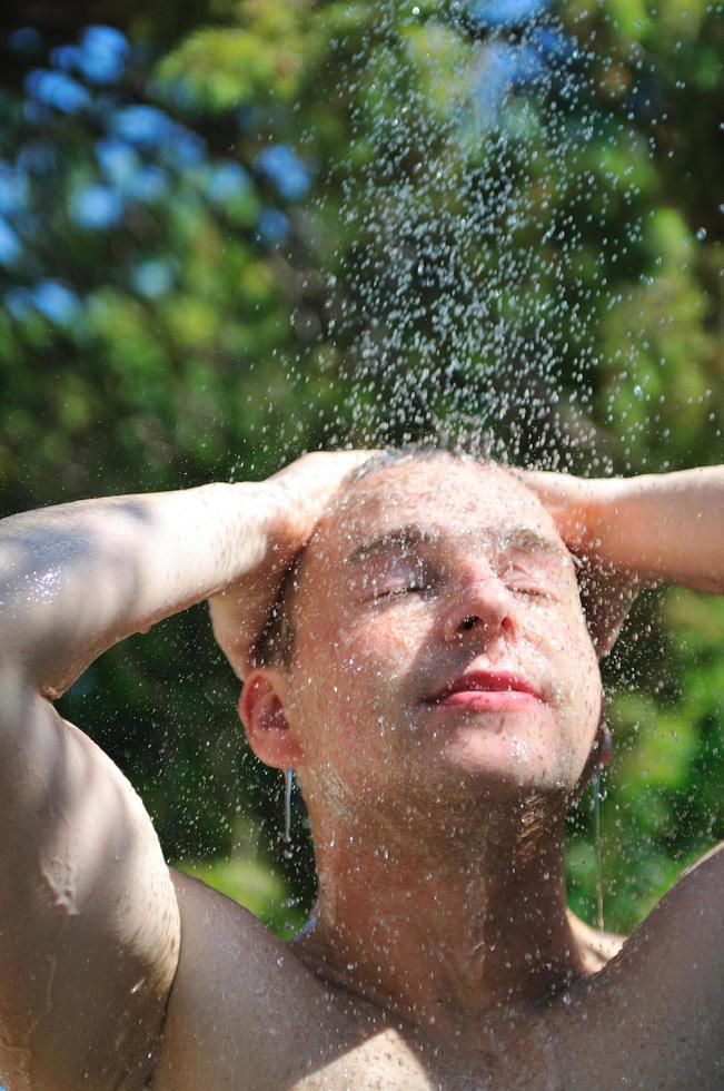 young man relaxing under shower photo