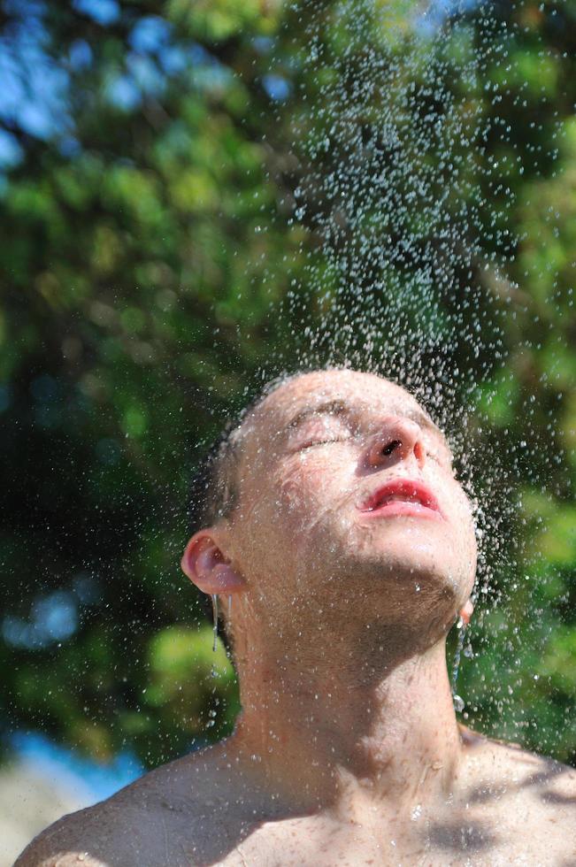 young man relaxing under shower photo