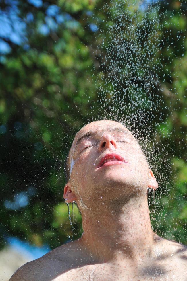 young man relaxing under shower photo