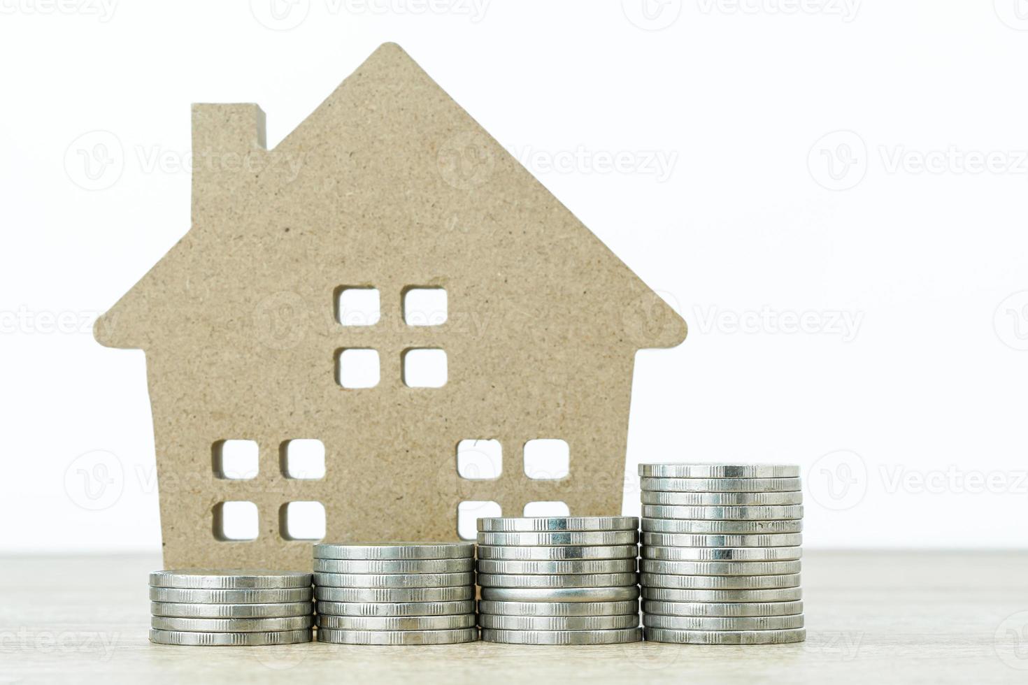 House model and stack of coins on table photo