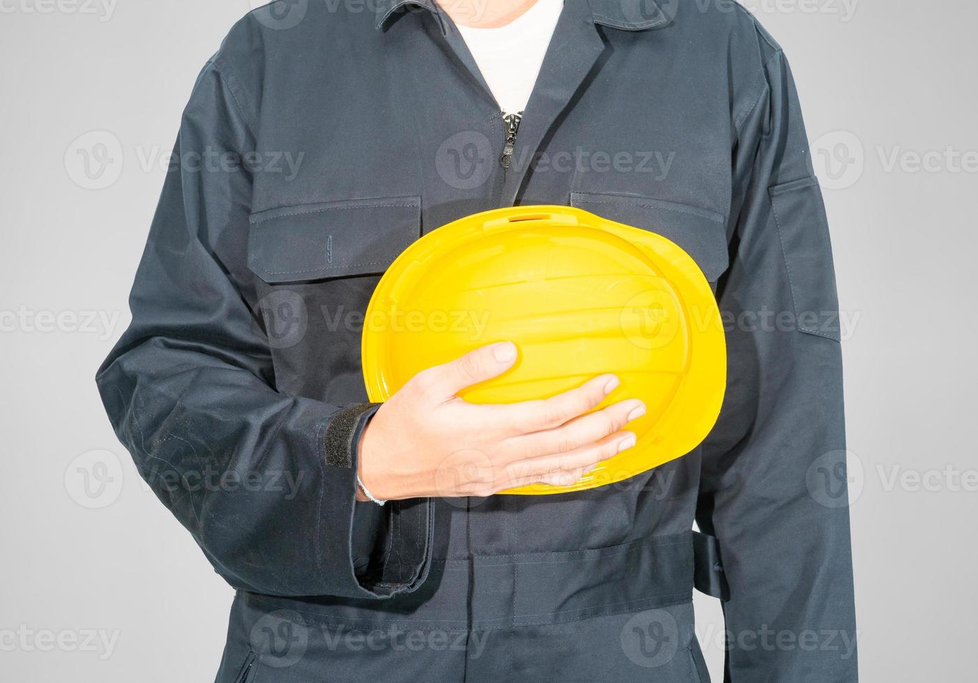 Close up Worker standing in blue coverall holding hardhat photo