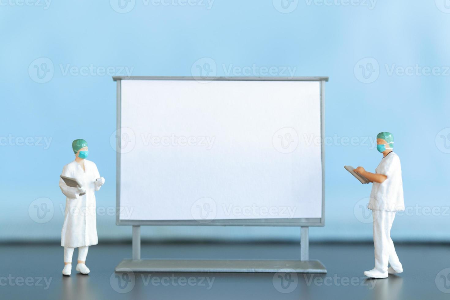 Miniature Doctor standing With Blank White Board photo