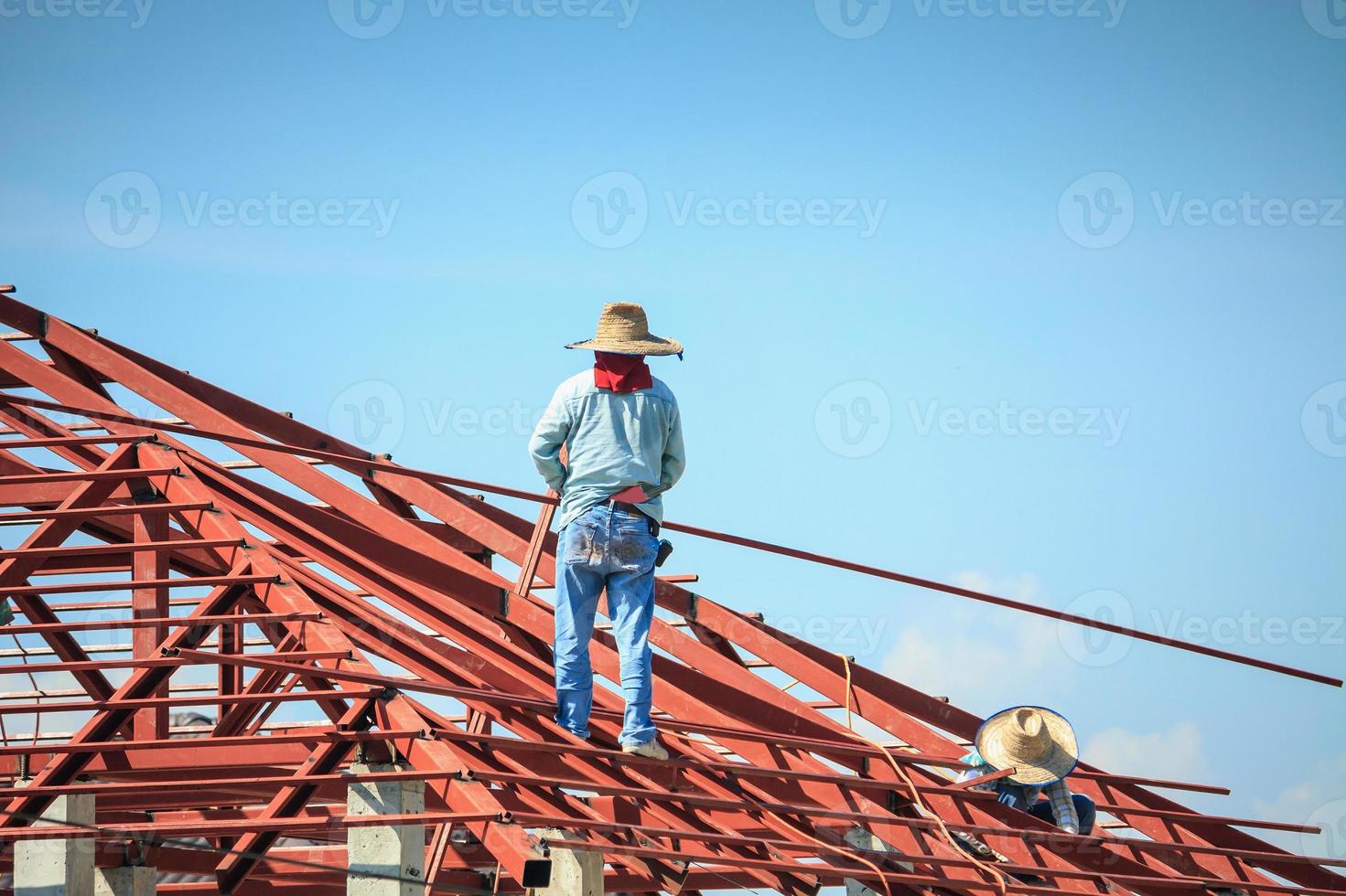 welder workers installing steel frame structure of the house roof at building construction site photo