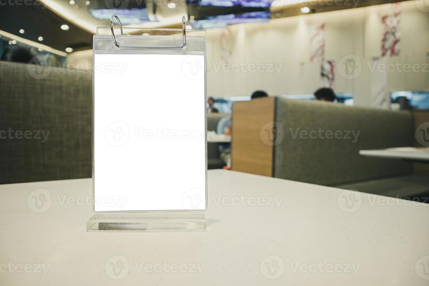 marco de menú de etiqueta blanca vacío de maqueta en la mesa con fondo interior de restaurante cafetería foto