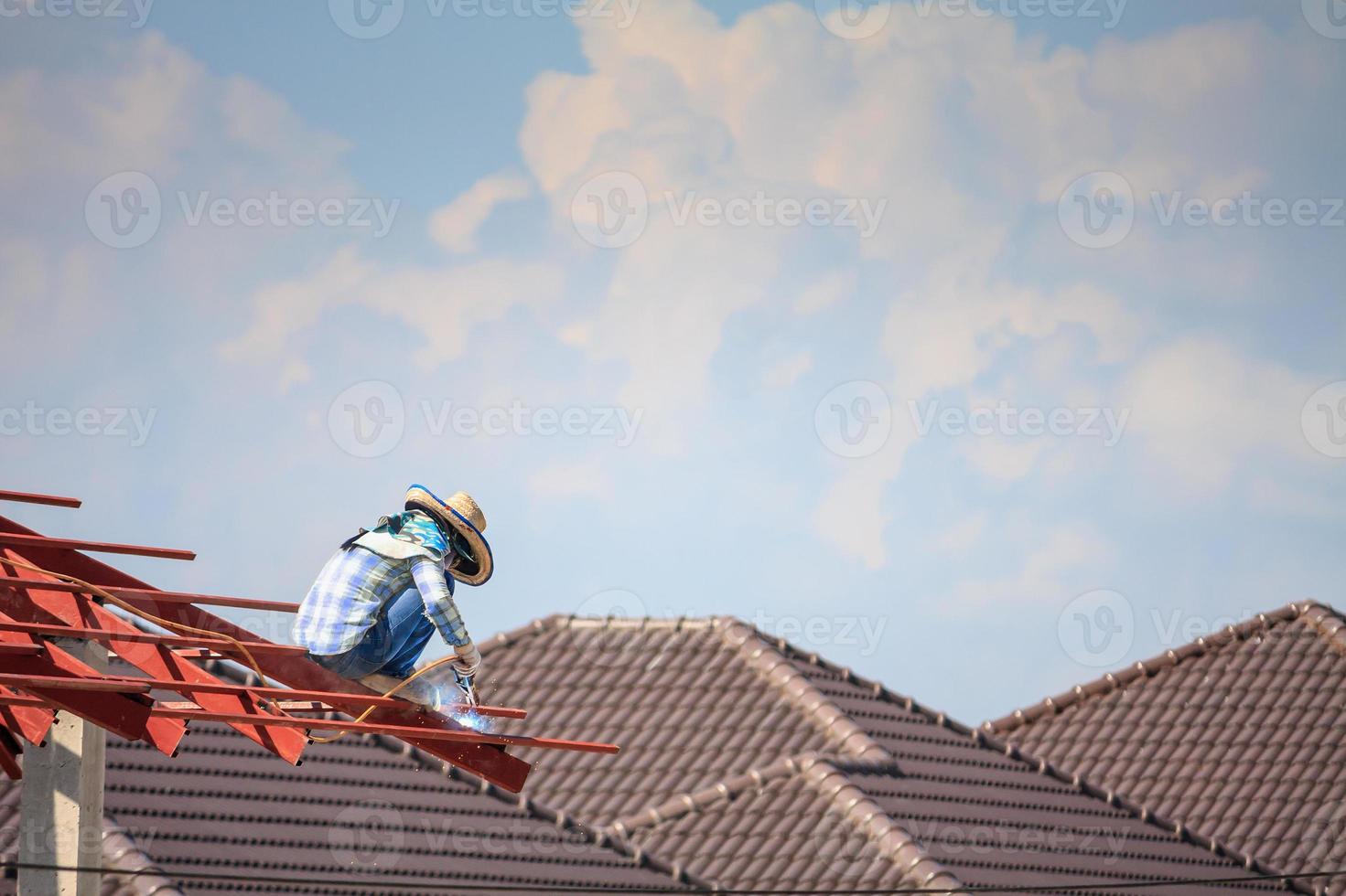 trabajadores soldadores que instalan la estructura de acero del techo de la casa en el sitio de construcción foto