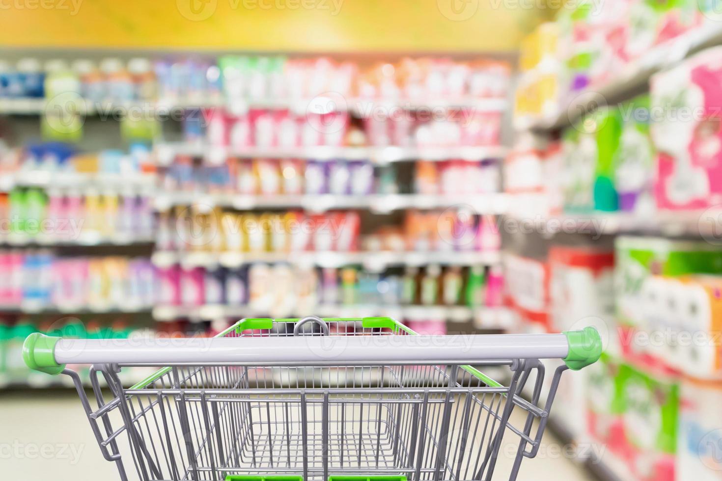 detergent and cleaning product shelves in supermarket or grocery store with empty shopping cart photo