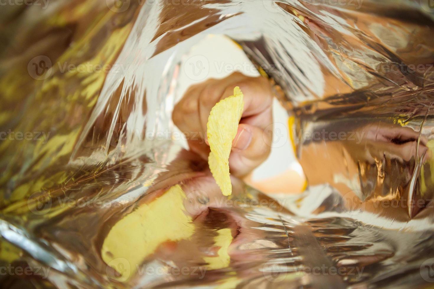 Sostenga a mano papas fritas dentro de una bolsa de aluminio para refrigerios foto