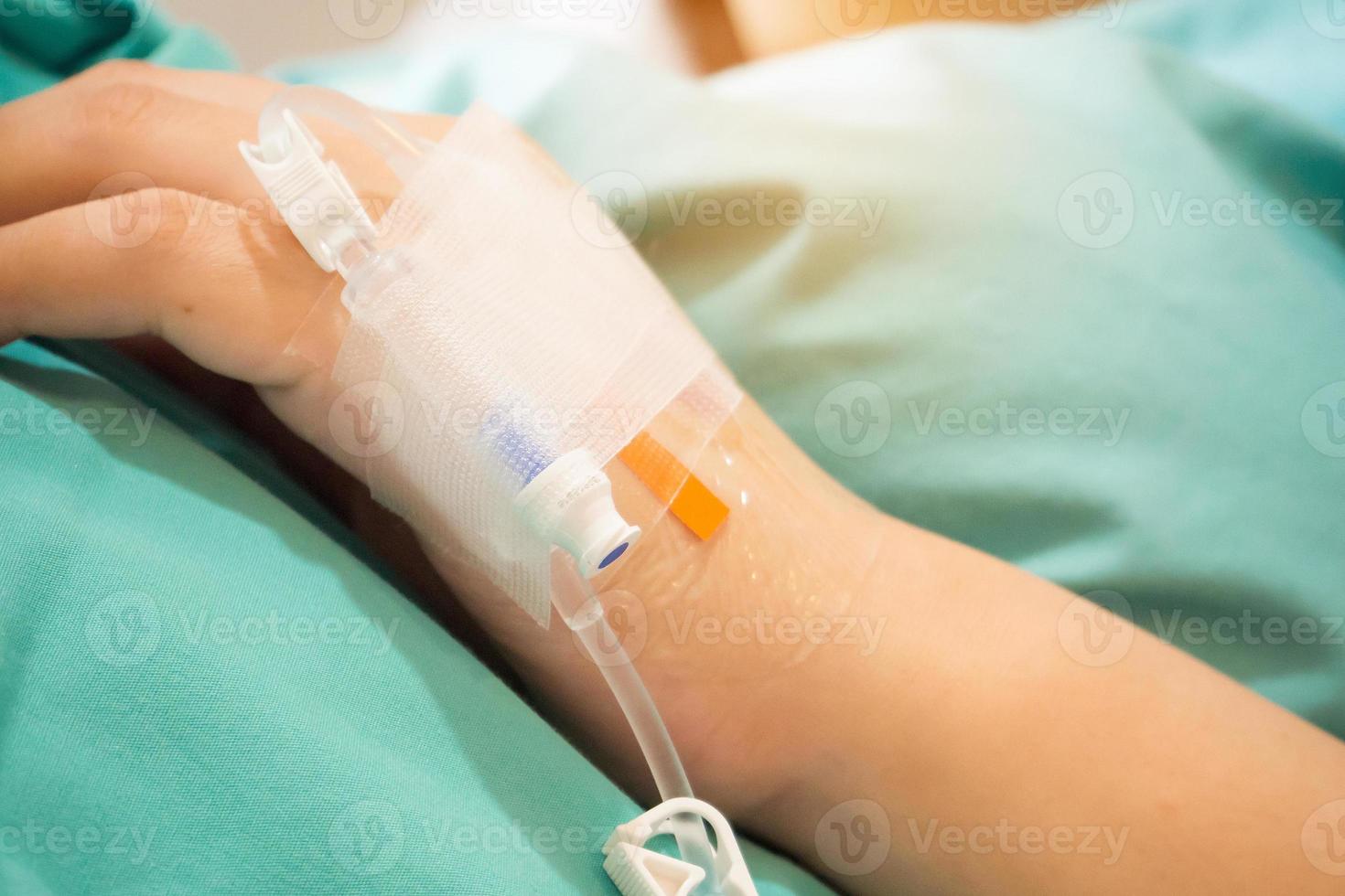 Asian woman patient hand on IV drip with saline solution, fluid replacement therapy photo