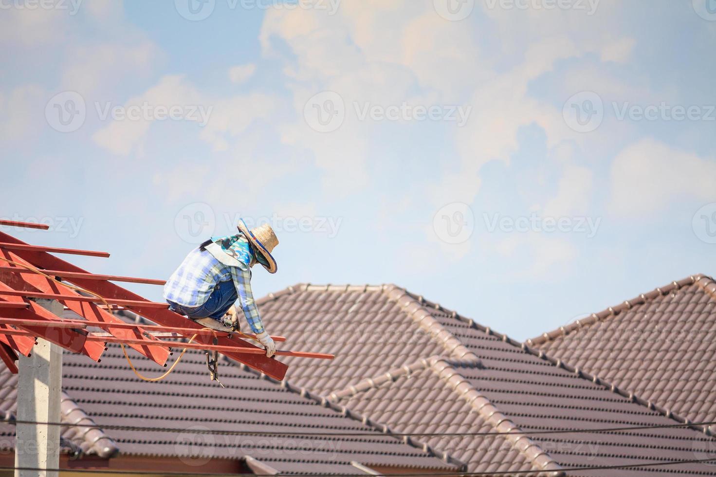 welder workers installing steel frame structure of the house roof at building construction site photo