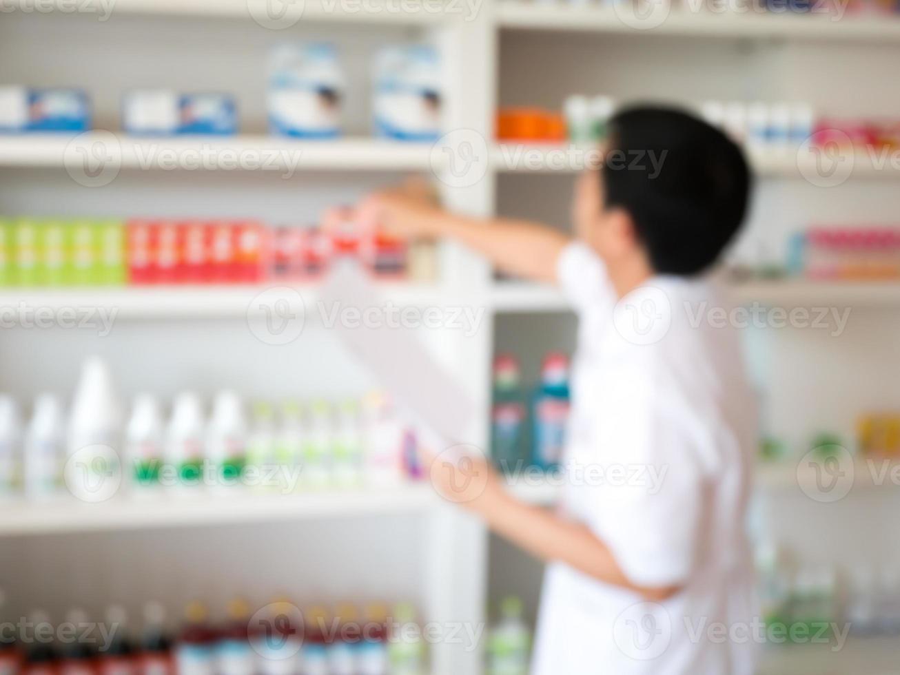 desenfoque farmacéutico tomando medicamentos del estante en la farmacia foto